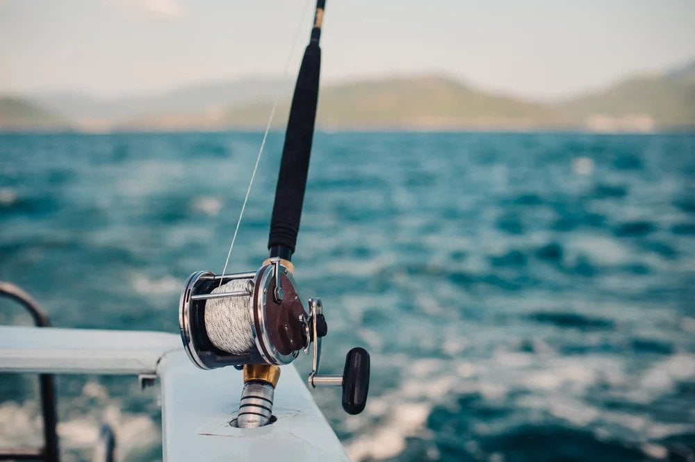 Fishing Rod Against Blue Ocean or Sea Background, Copy Space